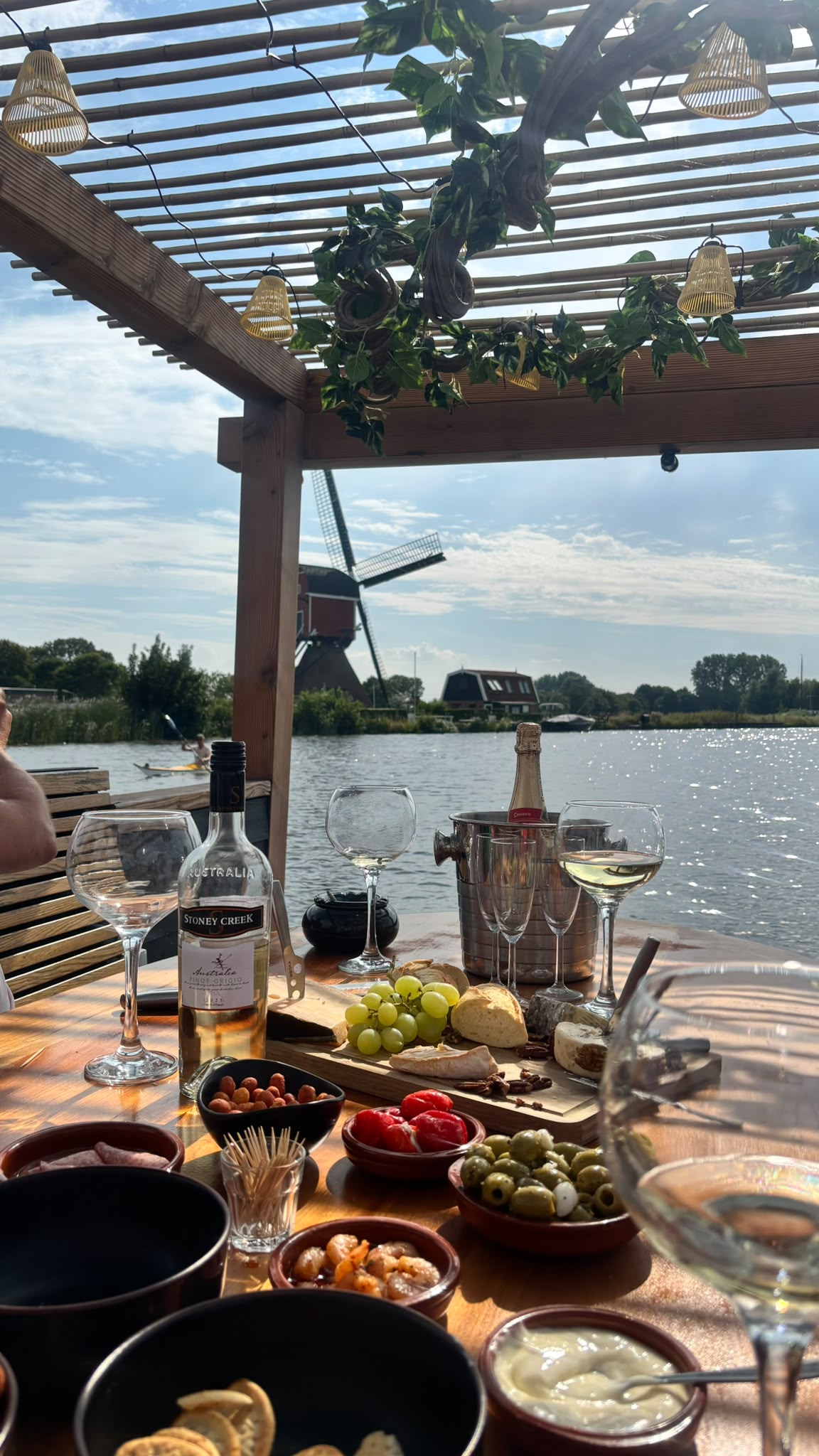 Borreltafel met hapjes en wijn, met een Hollandse molen aan het water
